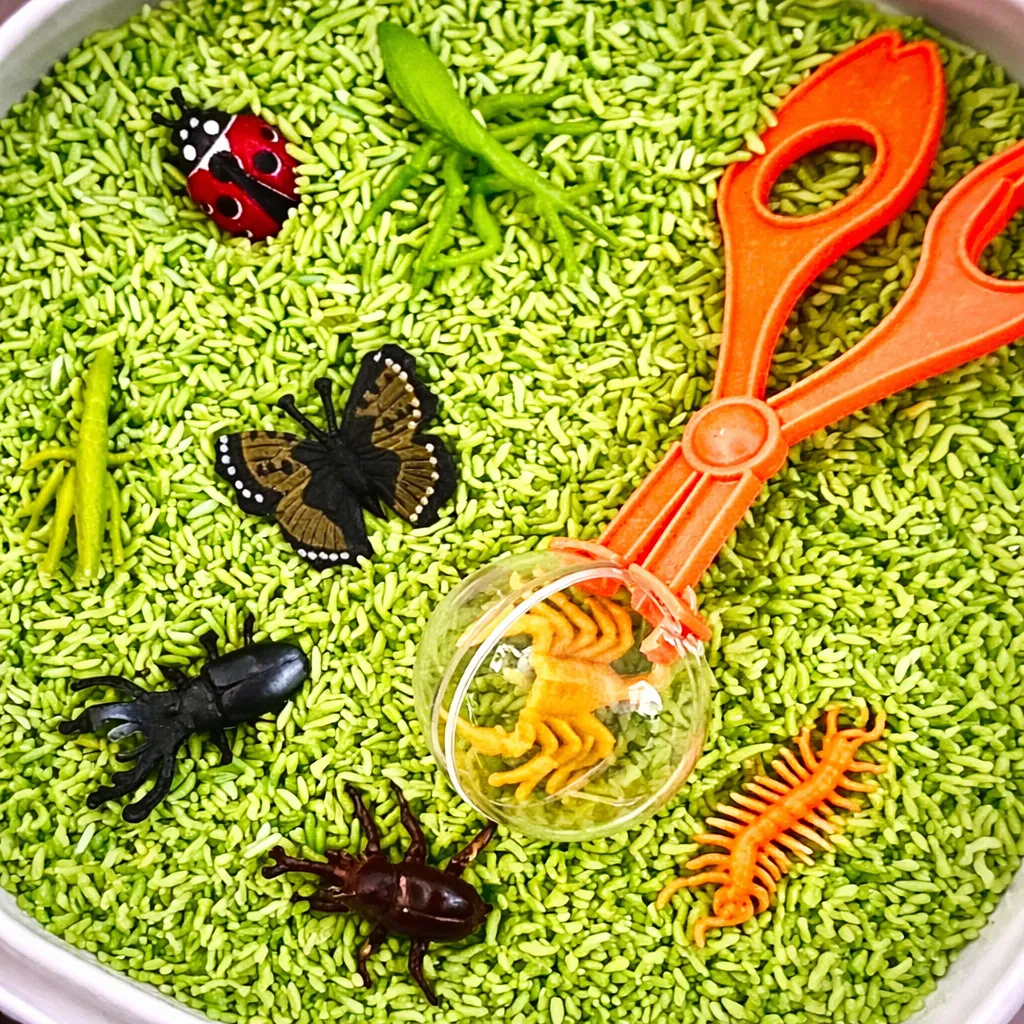 Sensory play bin with dyed rice, toy insects, scoops, and nature-themed materials for kids